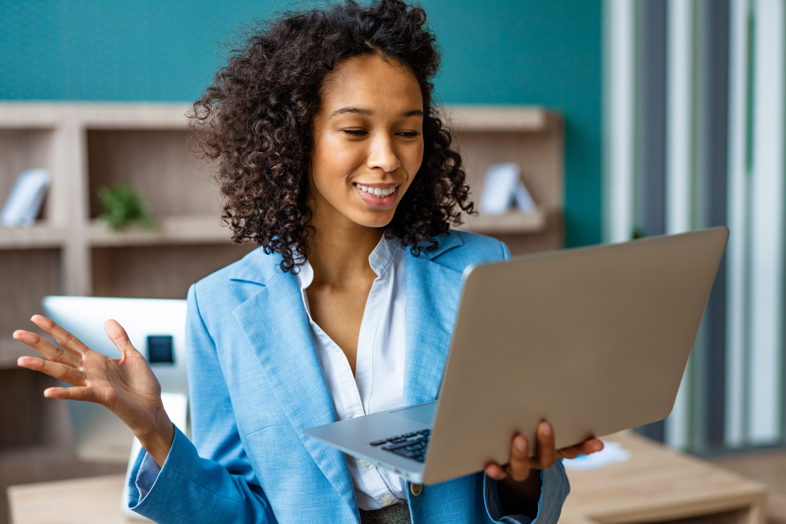 Woman standing in an office holding up a computer